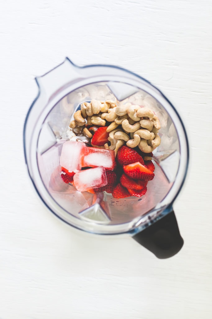 Strawberry Shortcake Smoothie Ingredients in a blender (ice, strawberries, cashews).