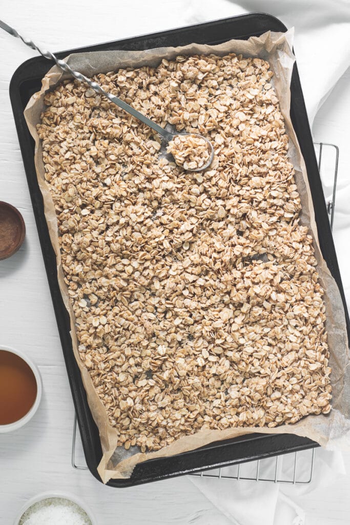 A baking sheet with evenly spread oats ready to be baked.