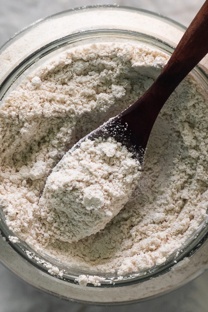 Close up fine and fluffy oat flour with a spoonful being scooped out.