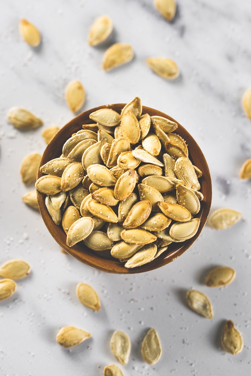 An overflowing bowl of golden-brown pumpkin seeds.