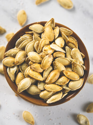 An overflowing bowl of perfectly roasted, golden-brown pumpkin seeds.