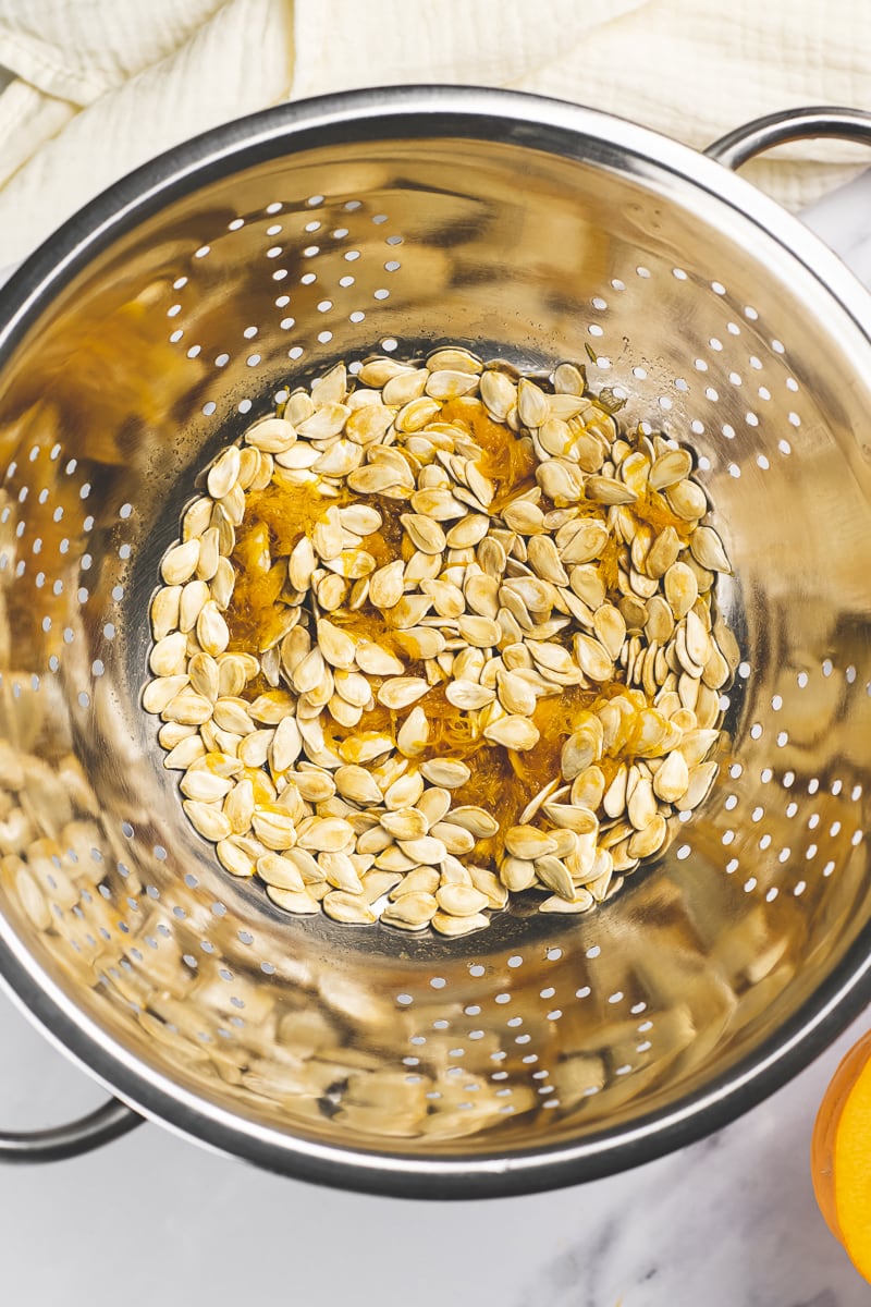 Pumpkin pulp and seeds poured into a colander.