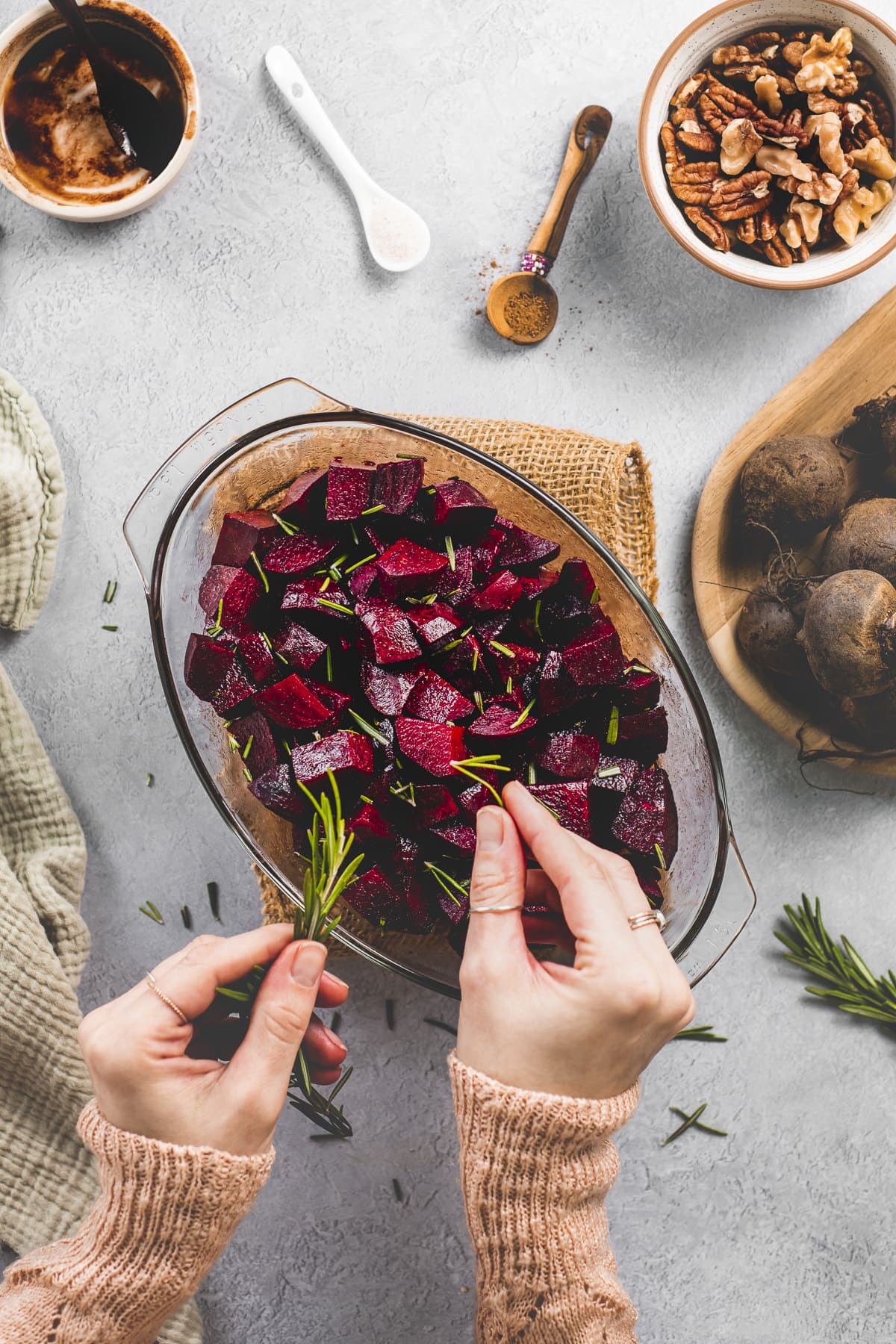 Rosemary being plucked from a fresh sprig and sprinkled over balsamic coated beets.