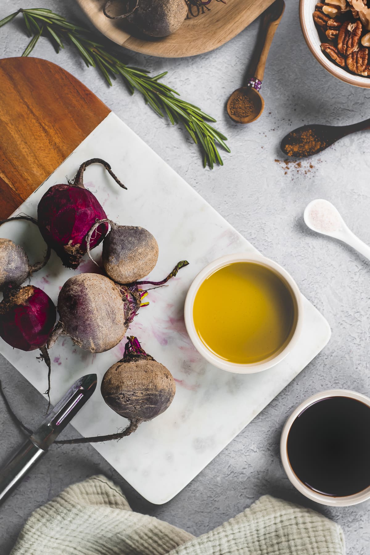 The ingredients needed to make a cinnamon and rosemary balsamic glaze measured out beside half peeled beets on a cutting board.