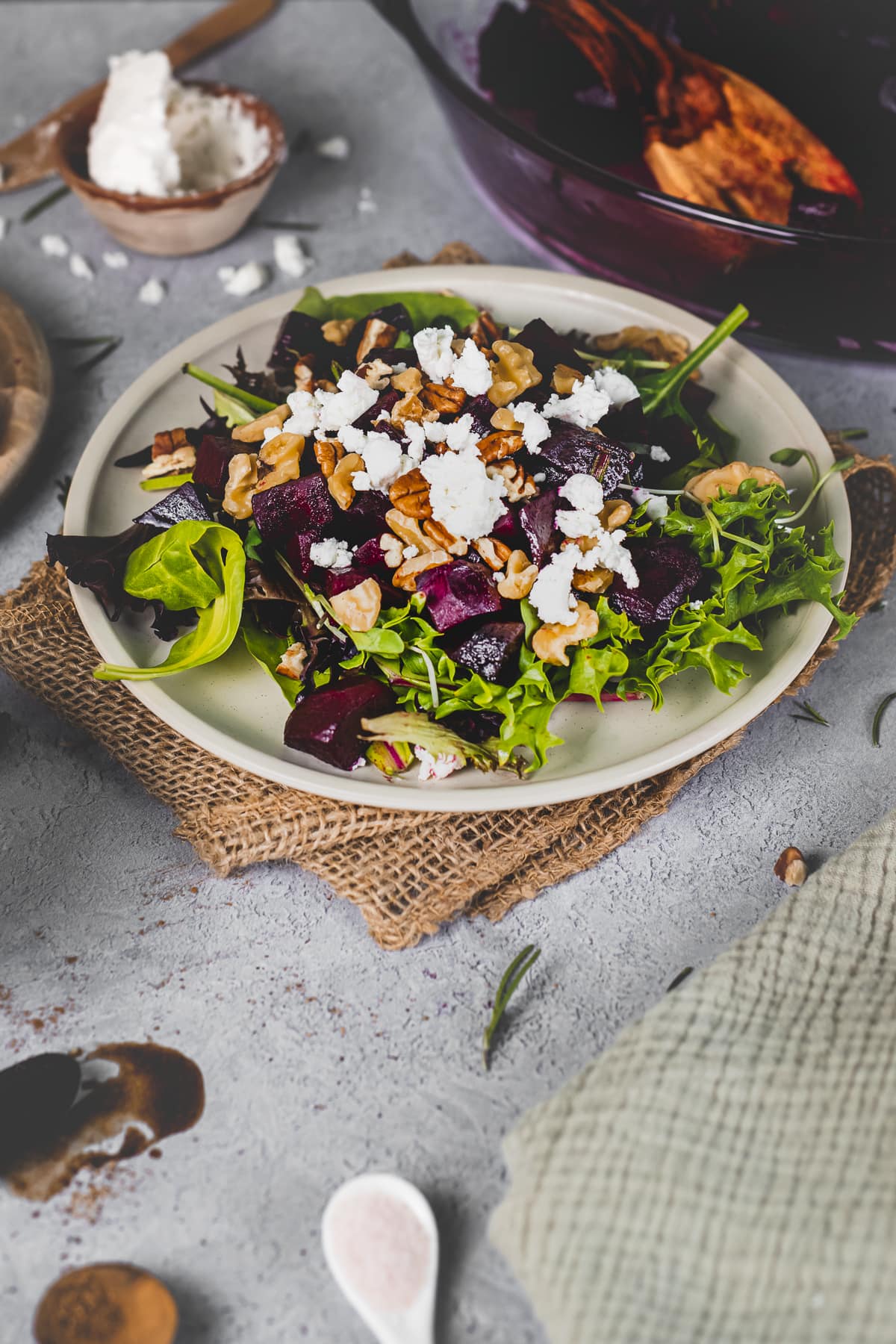 A plate of salad greens topped with roasted balsamic beets, soft goat cheese and lightly toasted pecans and walnuts.