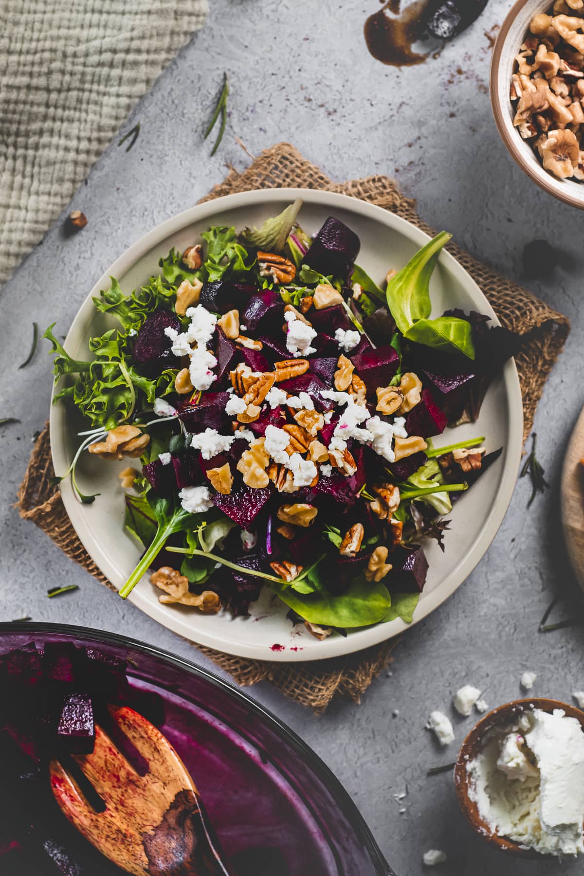 A plate of salad greens topped with roasted balsamic beets, soft goat cheese, walnuts and pecans.