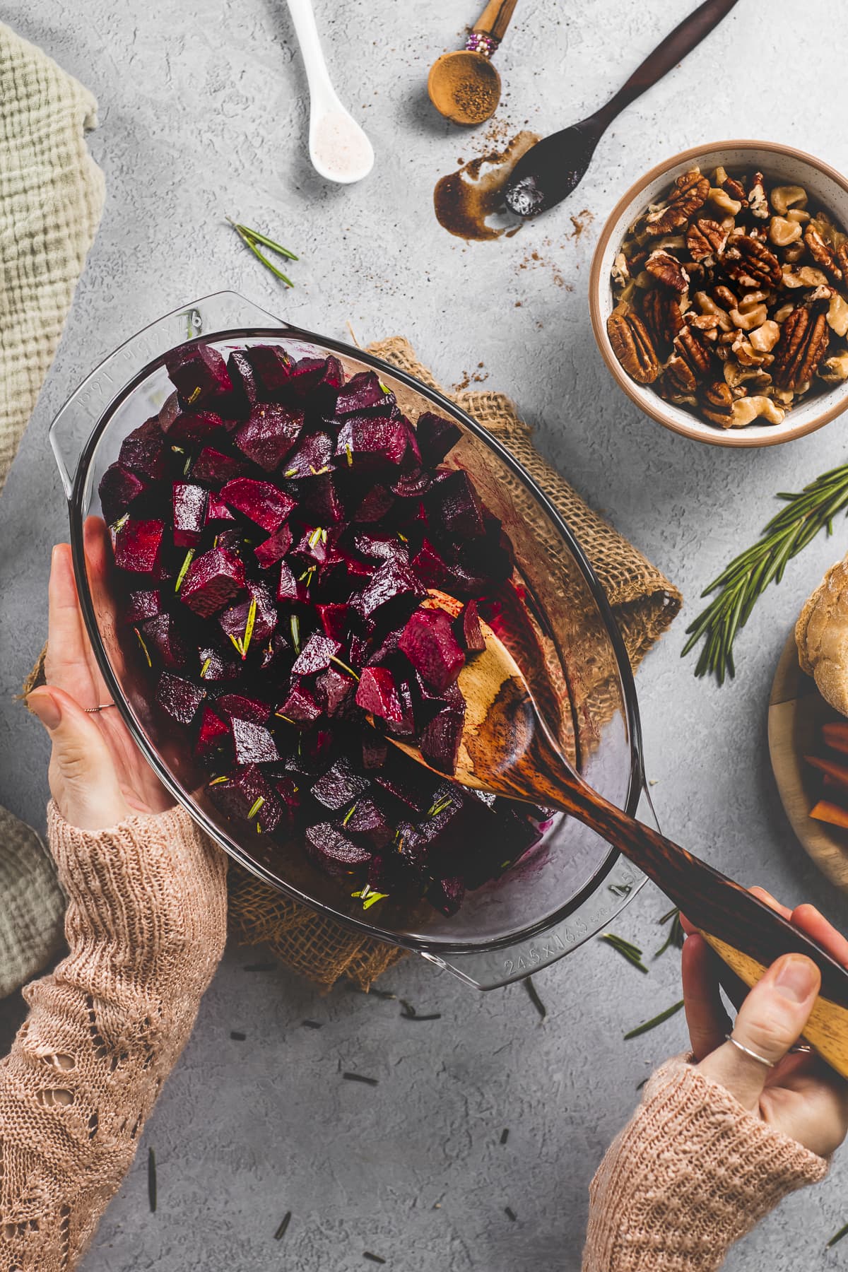 Roasted Cinnamon & Rosemary Balsamic Beets being scooped out of a roasting dish with a wooden serving spoon.