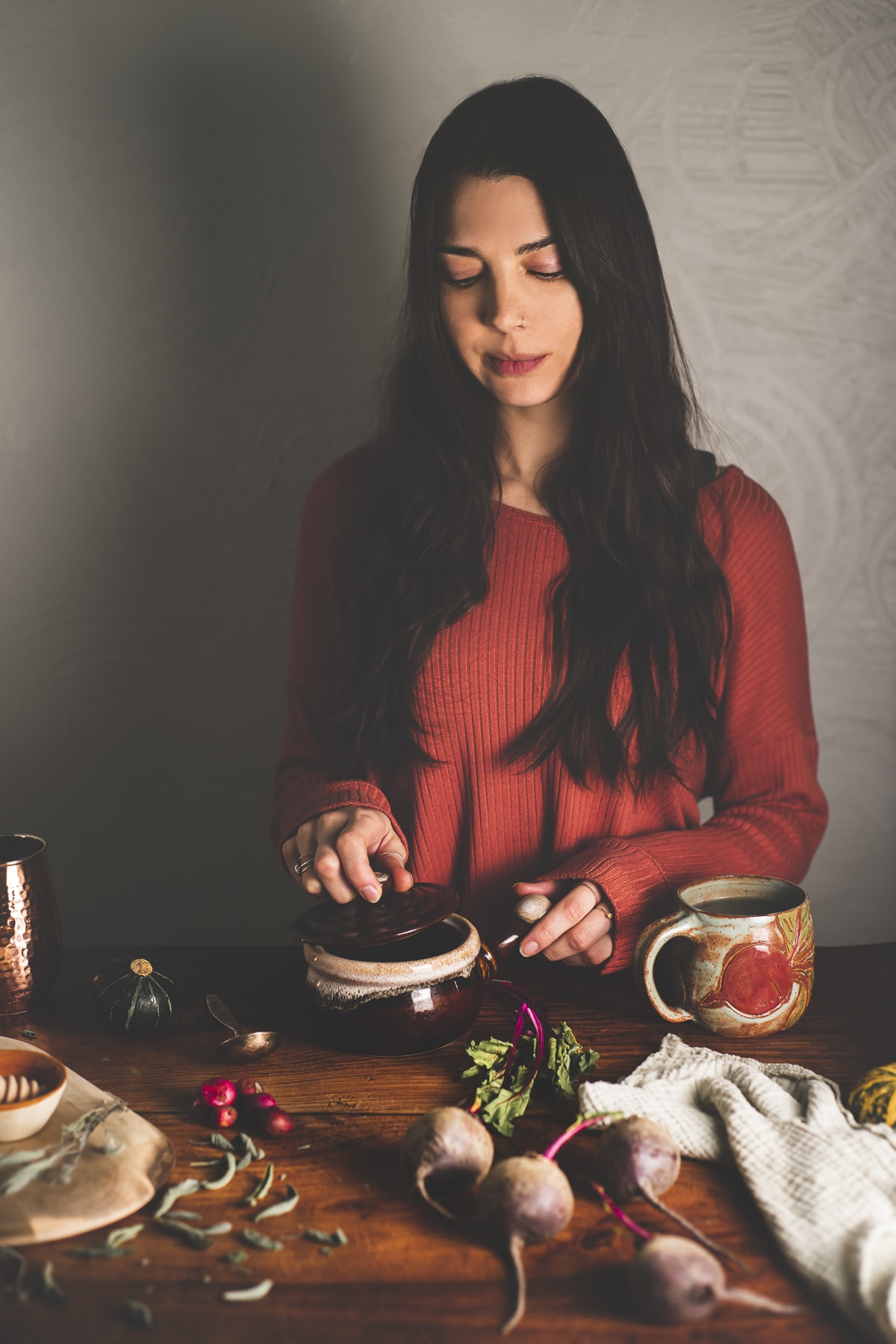 A woman preparing whole foods on a rustic table with fresh beets and beet greens.