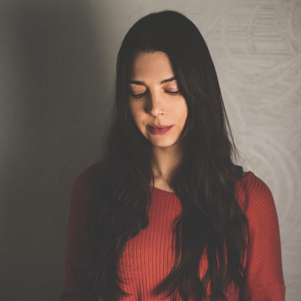 A woman with long hair hair looking down while preparing a whole food meal.