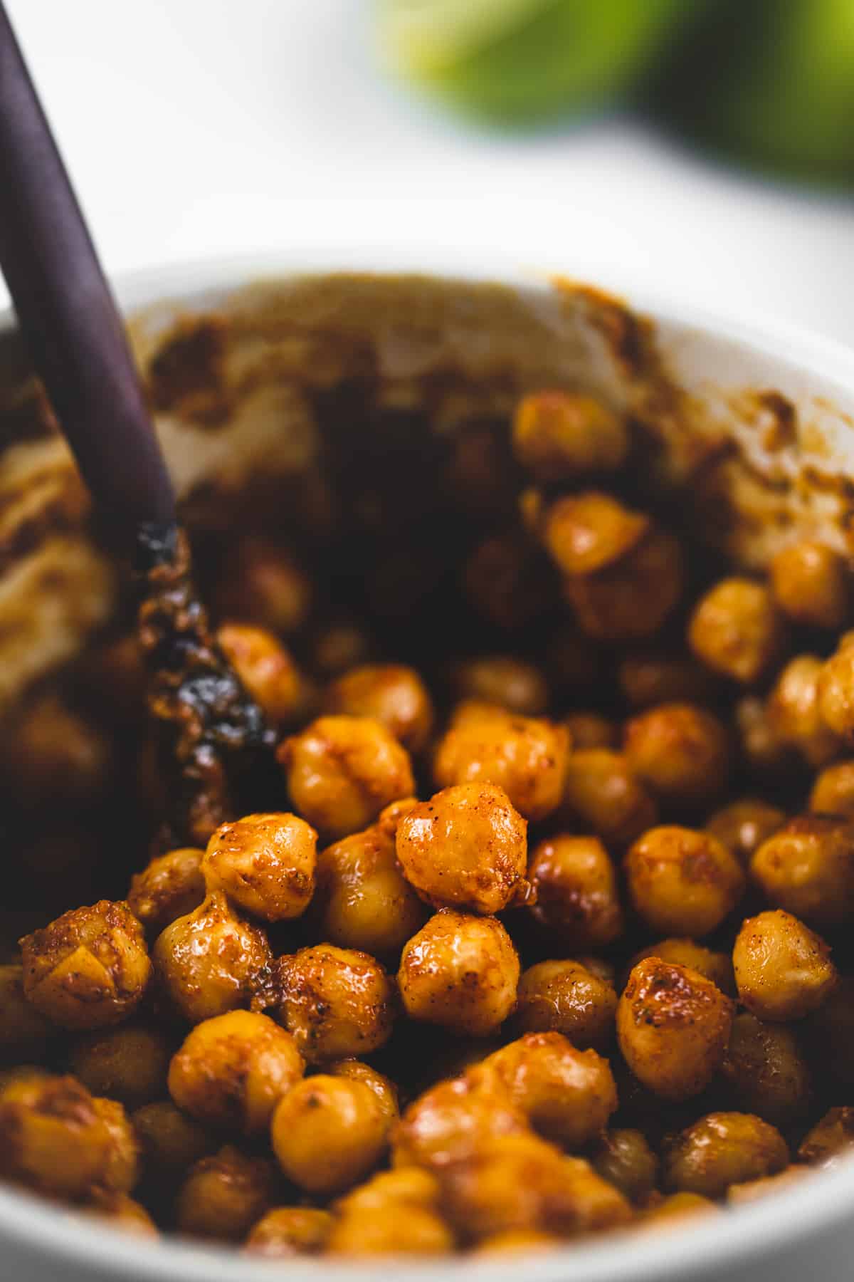 A bowl of chickpeas beings mixed with chili lime seasoning.