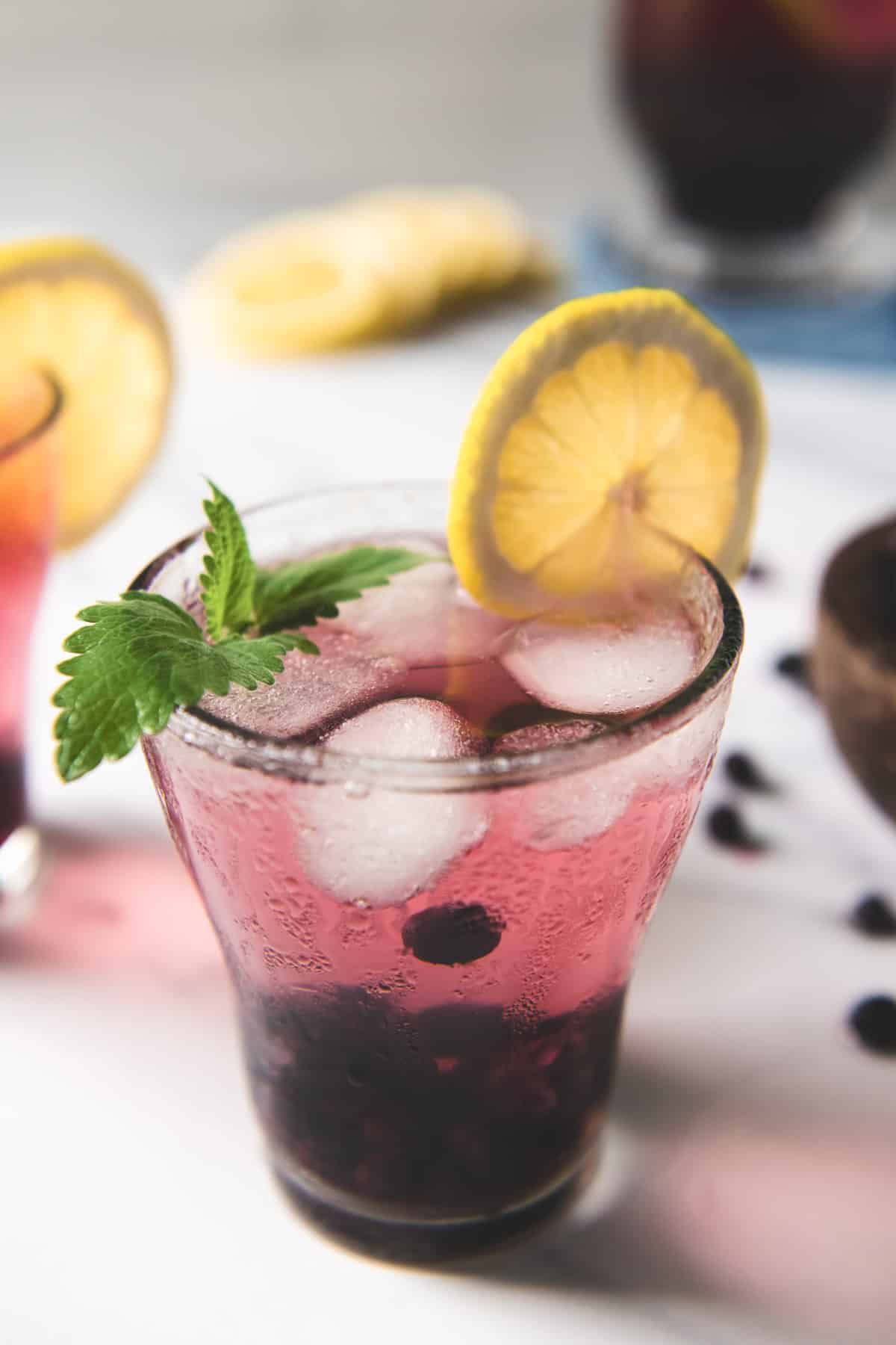 Infused blueberry water garnished with a slice of lemon and a sprig of fresh lemon balm.