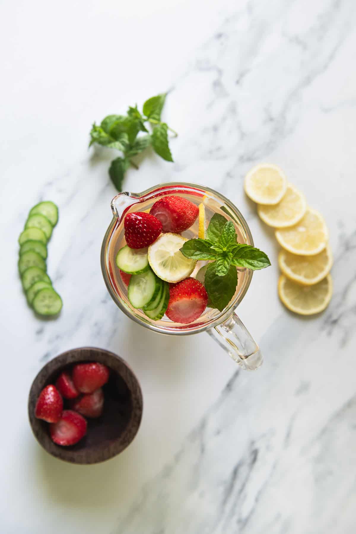 Infused water with strawberries, lemon and cucumber, garnished with a sprig of mint.