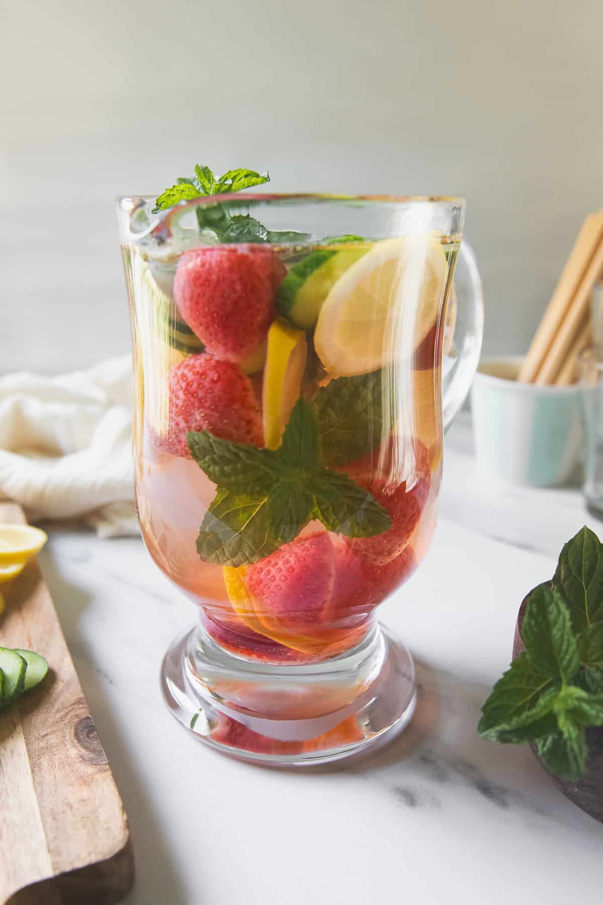 Lemon, mint, cucumber and strawberries infusing in a pitcher of water.