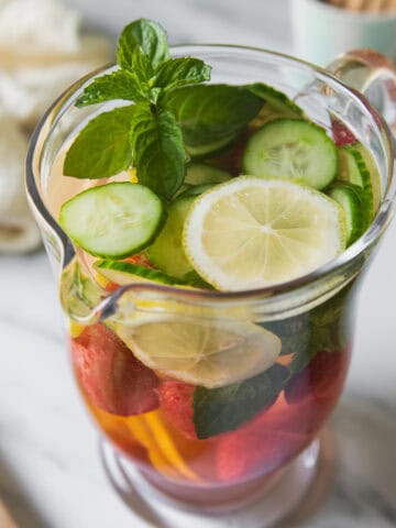 A pitcher of infused water with lemon, strawberries, cucumber and mint.