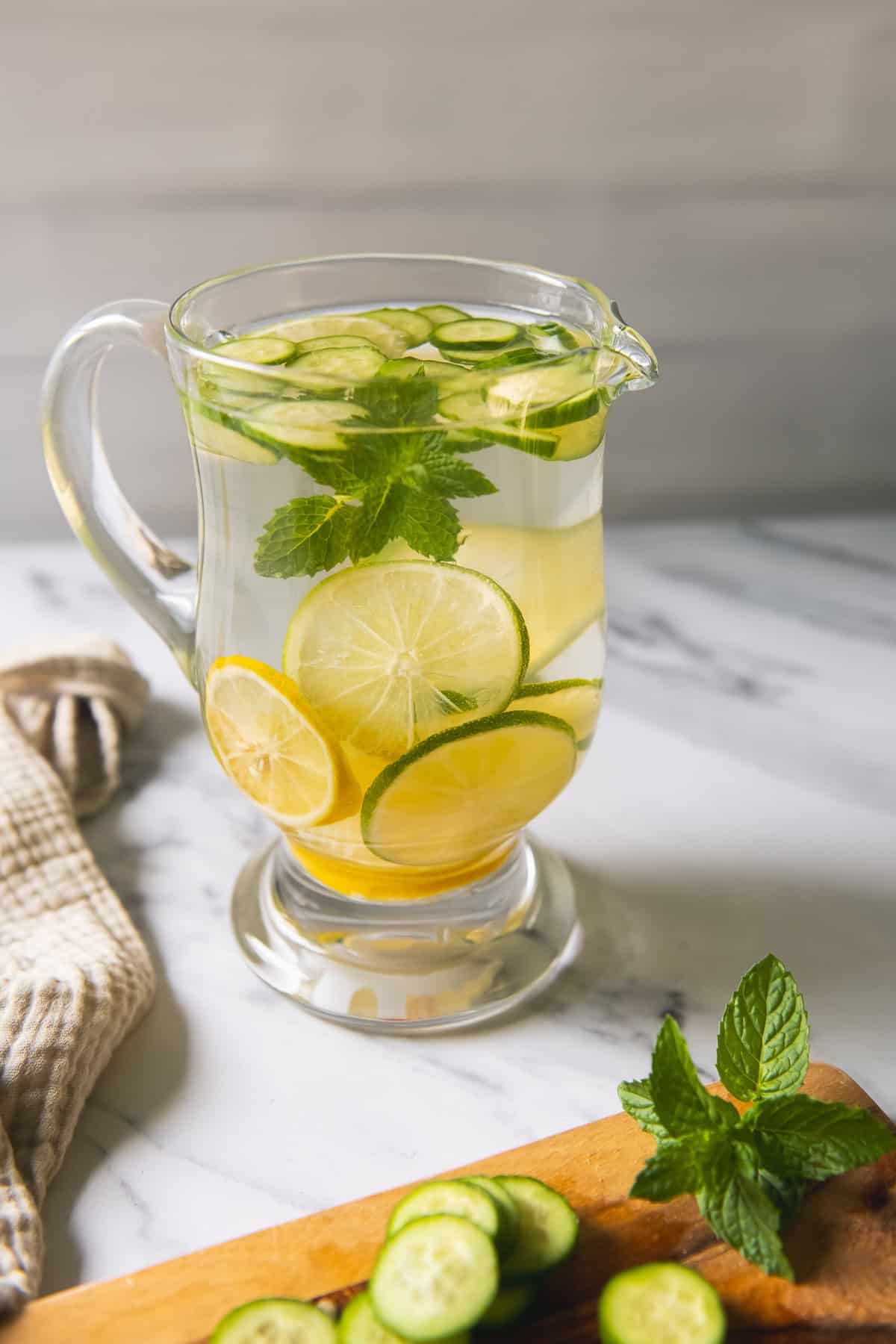 A pitcher of water infused with slices of lemon, lime, cucumber and a sprig of mint.