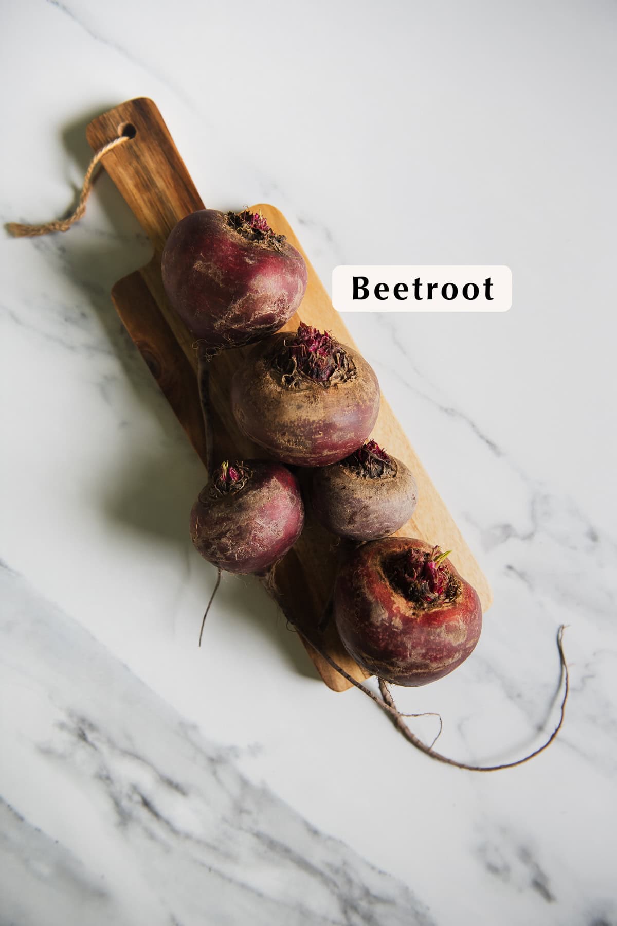 Washed Beetroot lined up on a wooden cutting board.