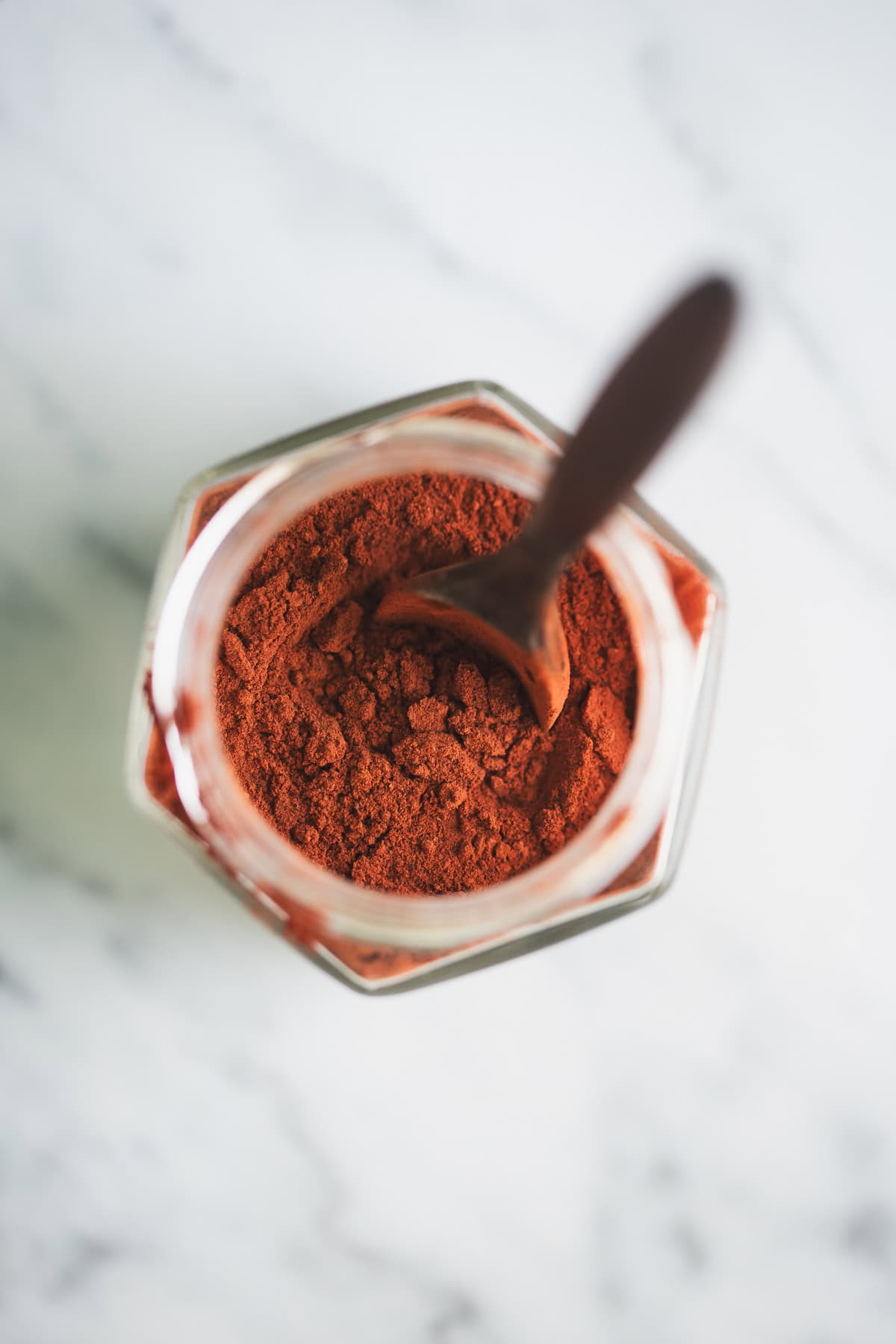A jar of beetroot powder with a wooden teaspoon.