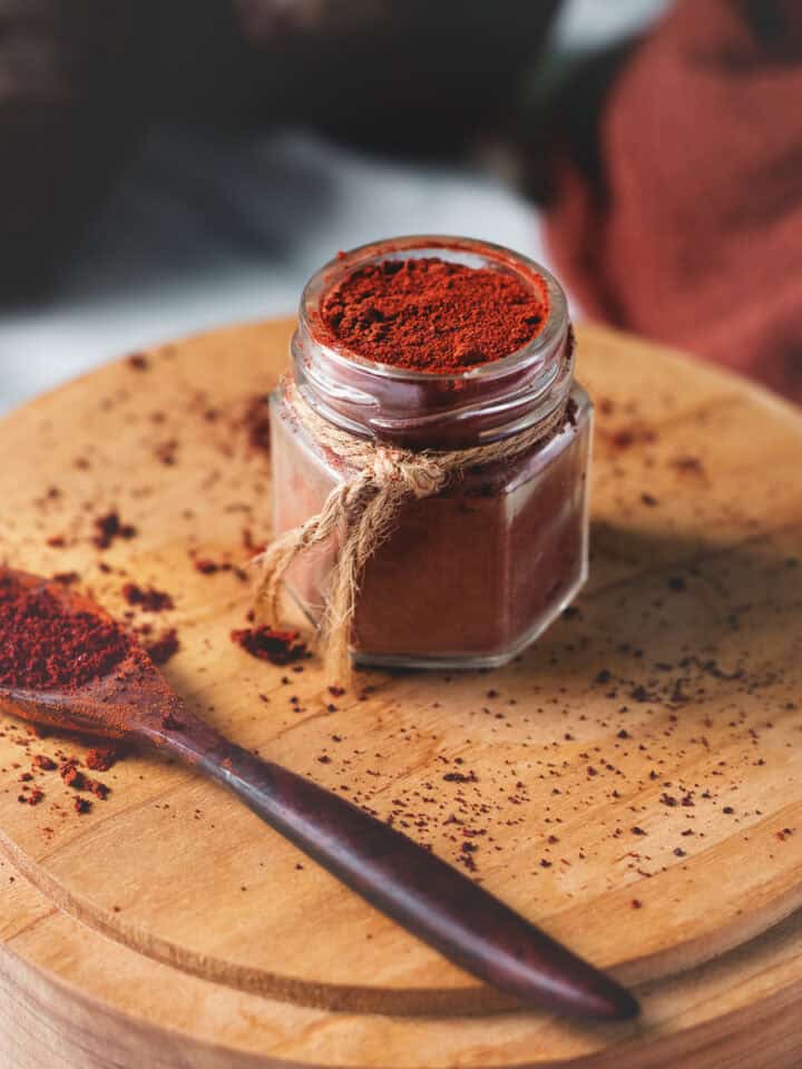 Freshly blended beetroot powder filled to the top of a jar and spilled all around.