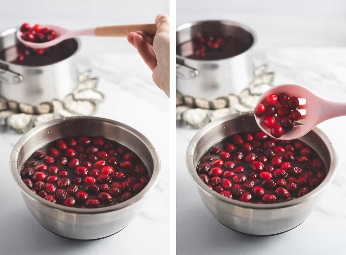 Blanched cranberries being scooped from a pot of hot water into a bowl of cold water with a slotted spoon.