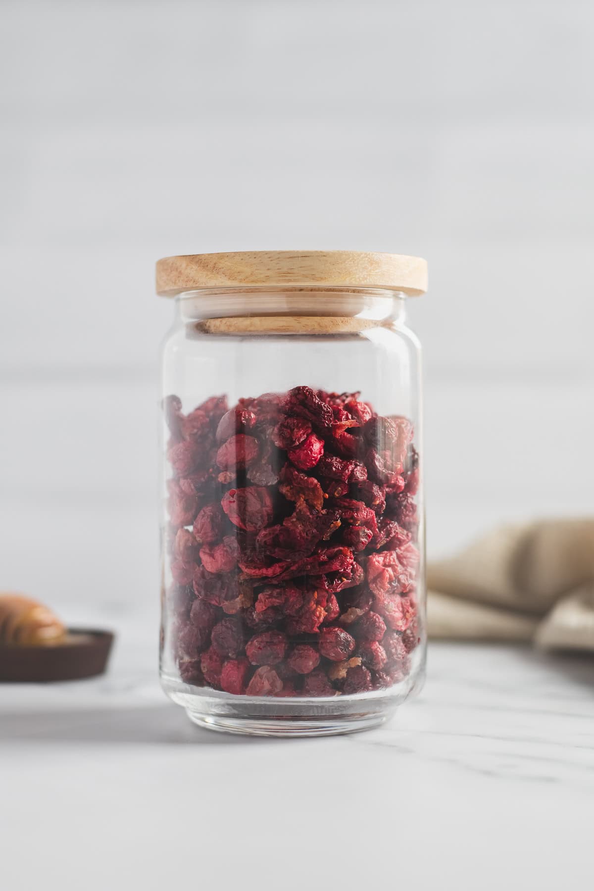 Dried cranberries in a glass jar with a sealed wooden lid.