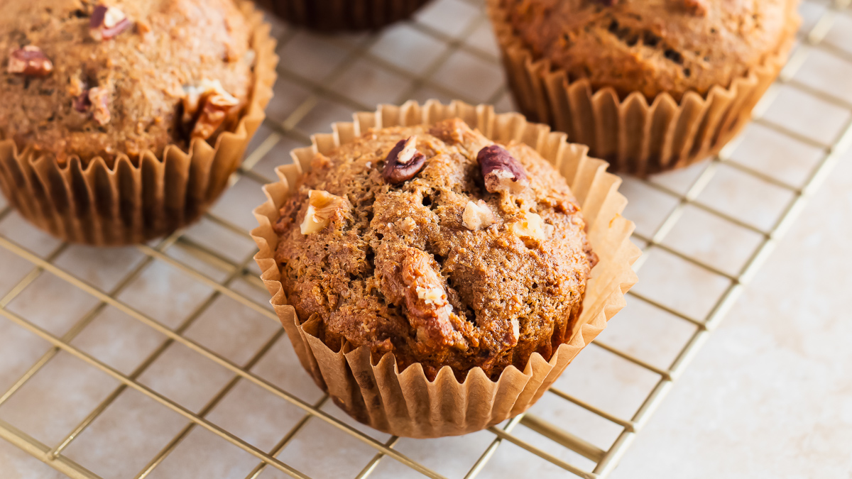 Banana muffins with walnuts and pecans on a cooling rack.