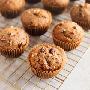 Banana muffins with walnuts and pecans on a cooling rack.