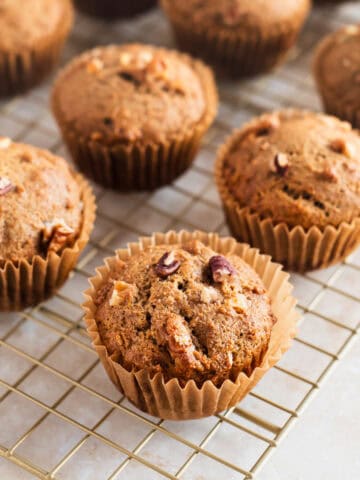 Banana muffins with walnuts and pecans on a cooling rack.