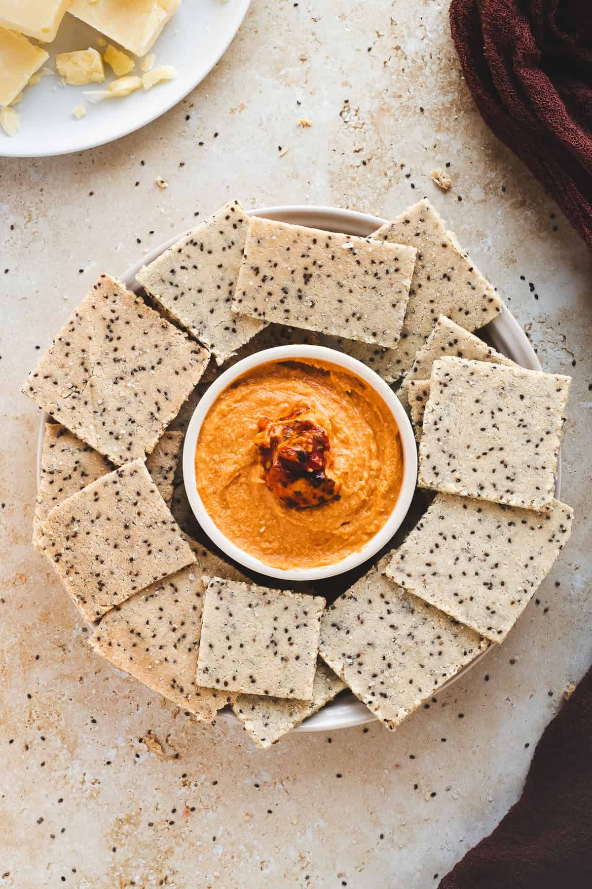 Crackers with chia seeds on a platter with hummus.