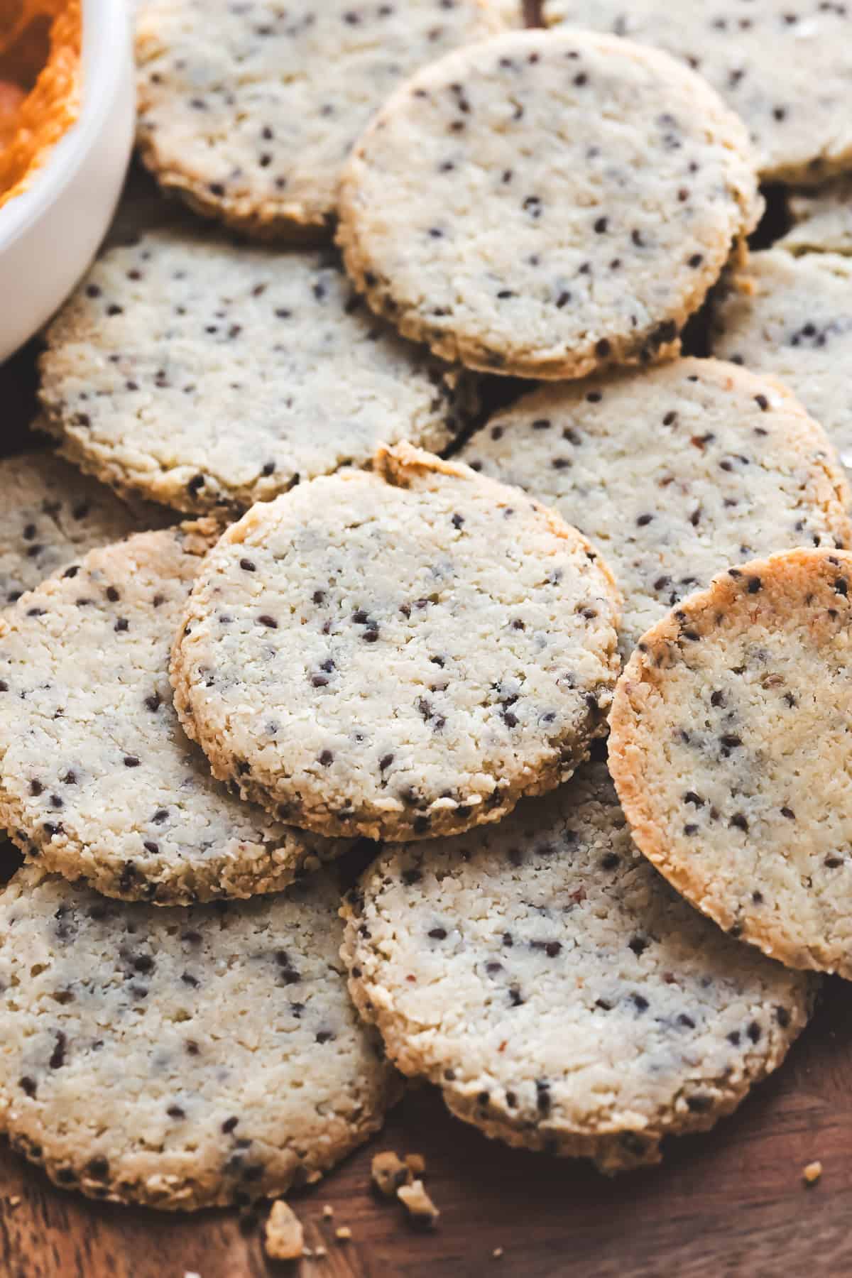 Round crackers with chia seeds, spread on a charcuterie board.
