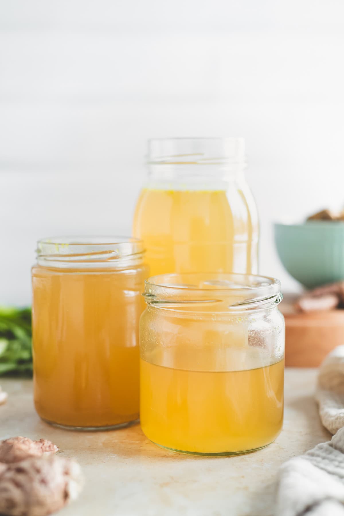 Three jars filled with golden chicken broth.