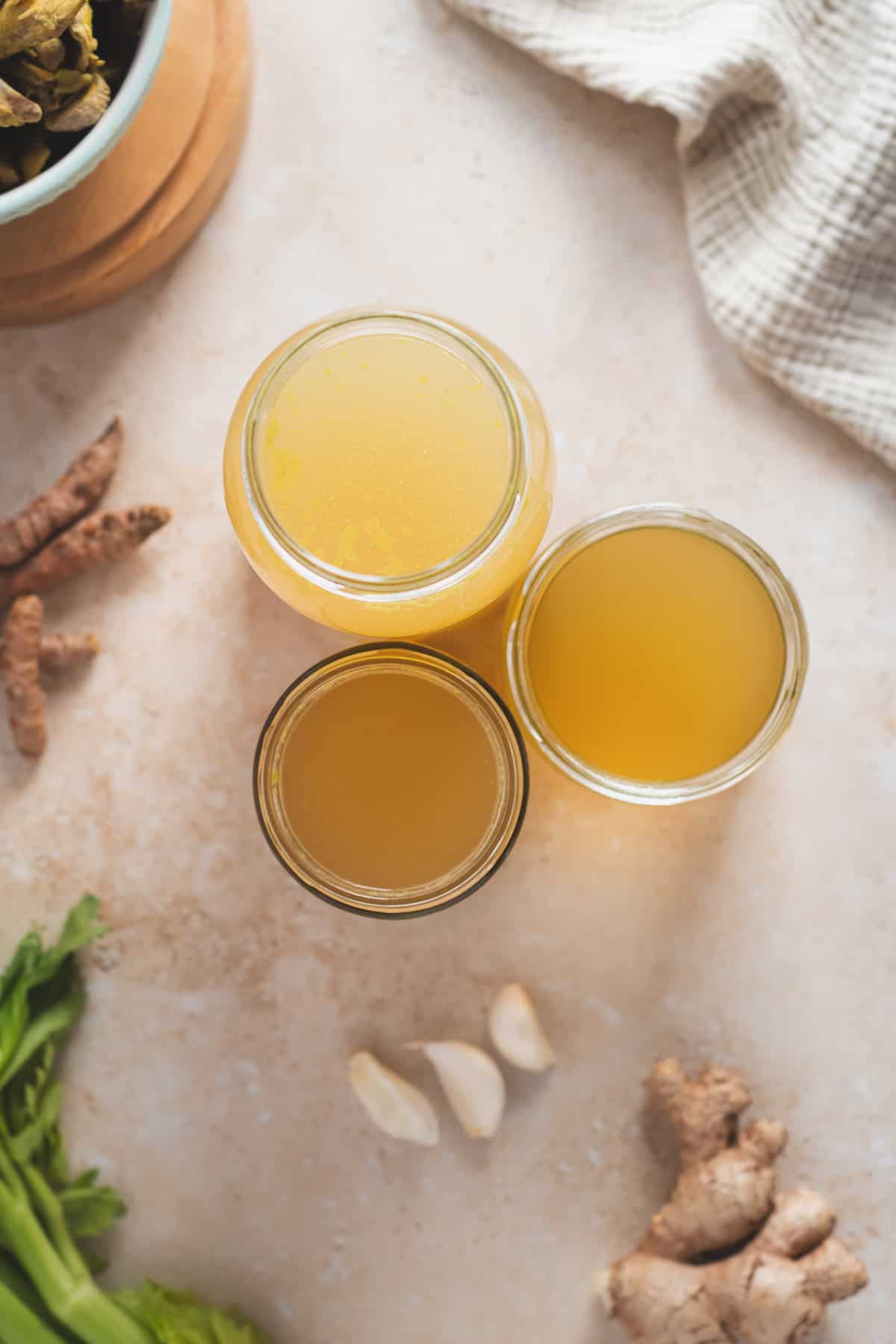 Glass jars filled with golden chicken broth.