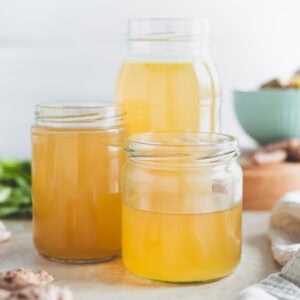 Three jars filled with golden chicken broth.