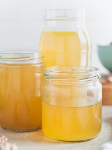 Three jars filled with golden chicken broth.