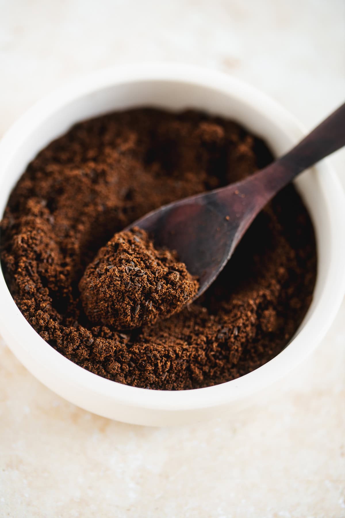 A spoon submerged in a bowl of finely ground vanilla bean powder.