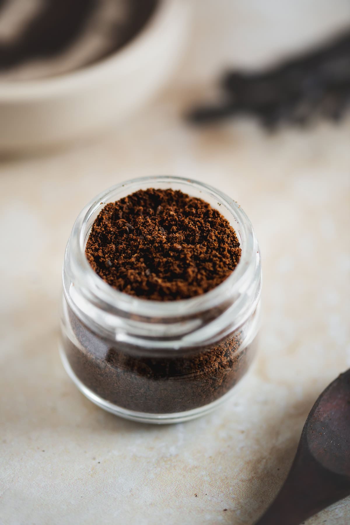 Vanilla powder in a jar in front of fresh vanilla beans.