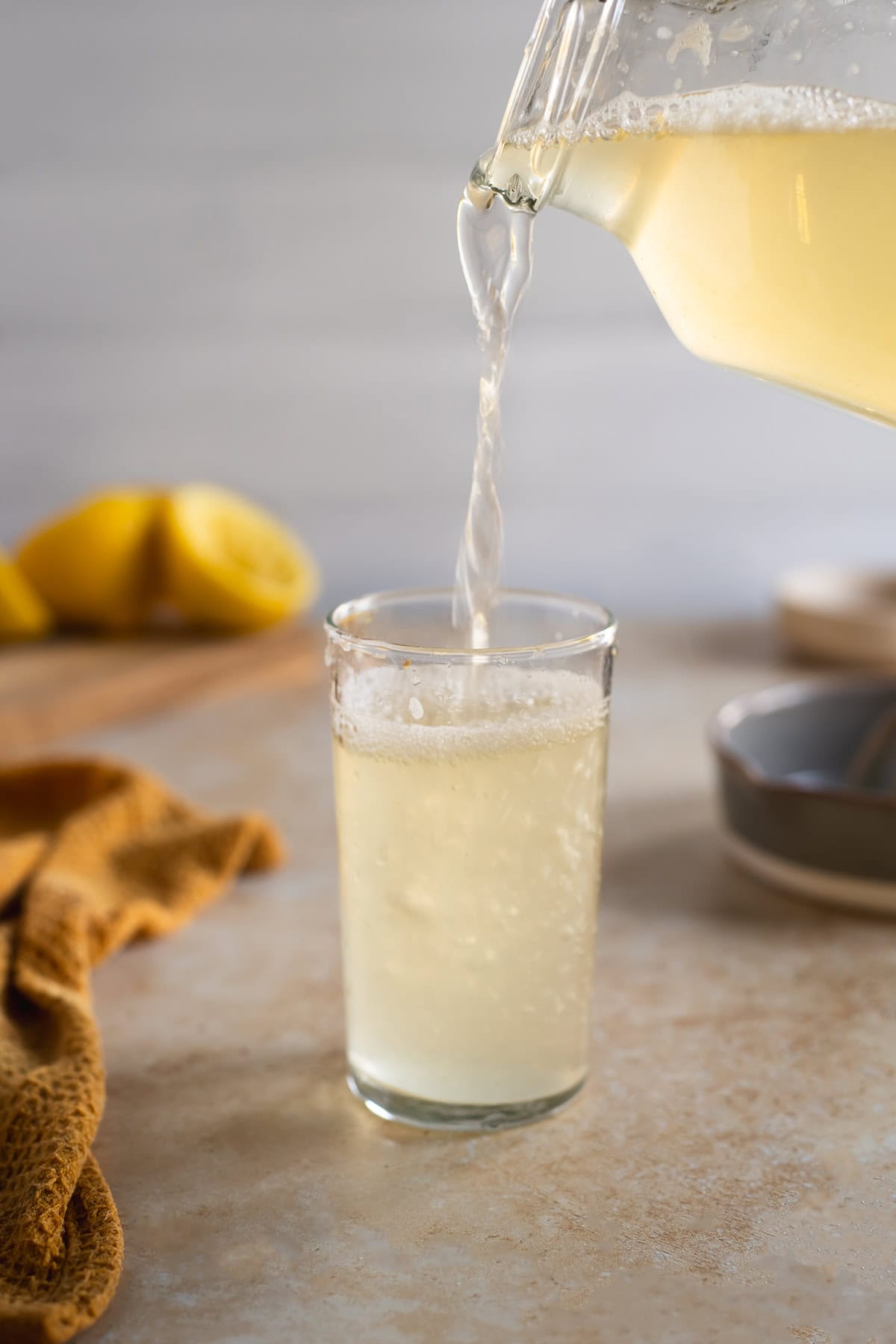 Fizzy lemon soda being poured into a drinking glass.