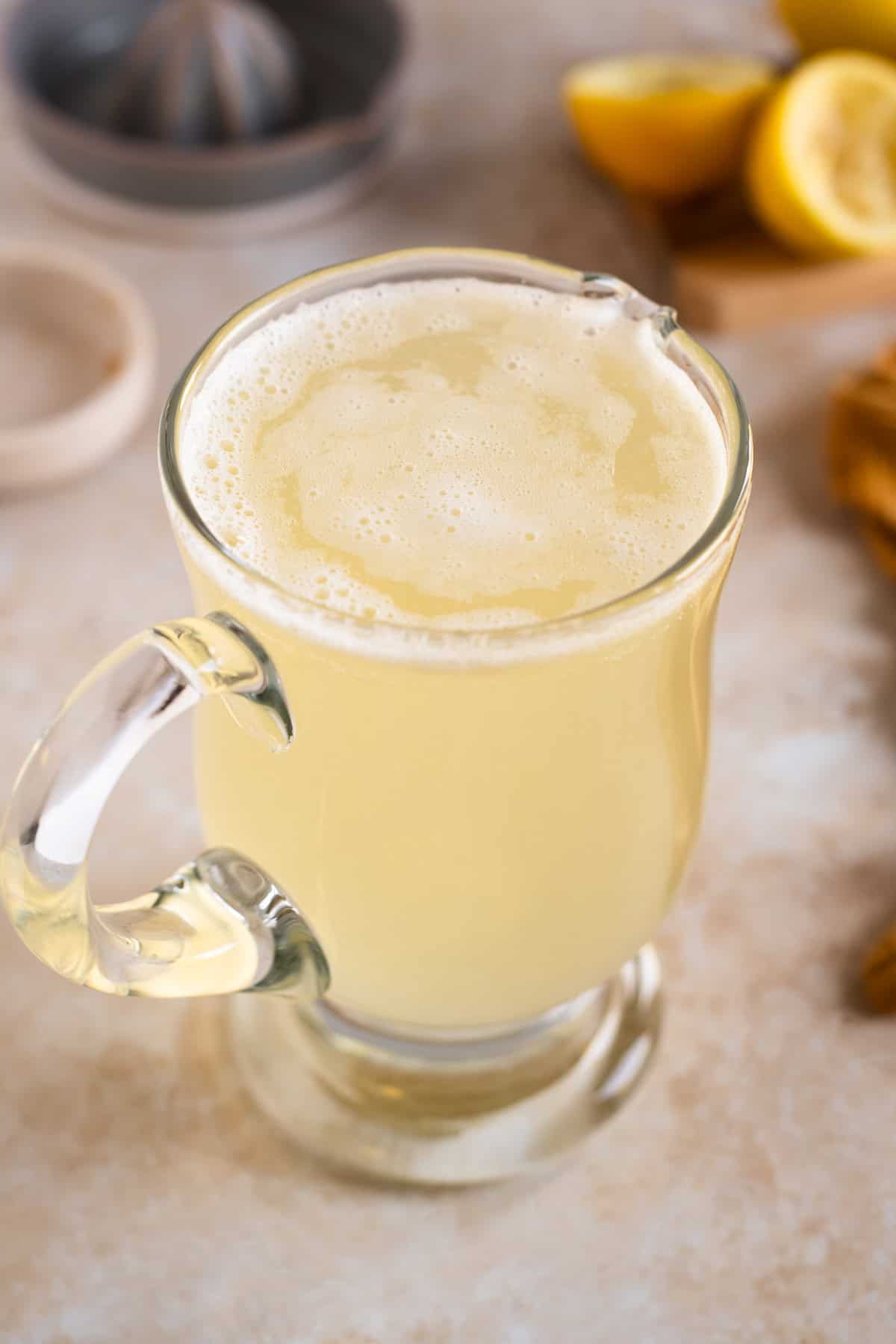 A glass pitcher filled to the top with lemon soda.