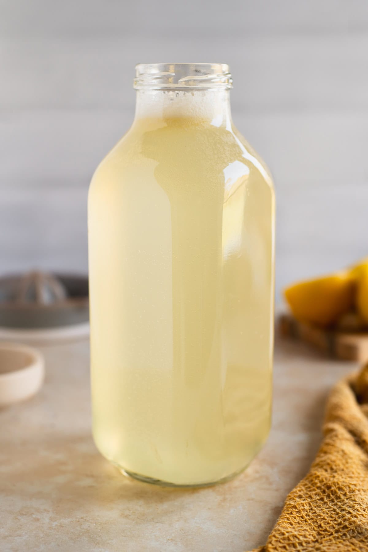 A glass juice jug filled with light yellow Lemon Soda.